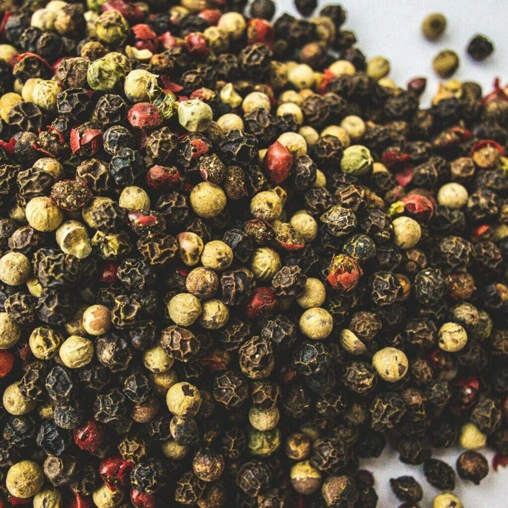 A mix of black, white, and red peppercorns scattered - see the science and research of resveratrol and black pepper - Get in the Rezzi Zone with organic resveratrol supplements for high performing men with black pepper